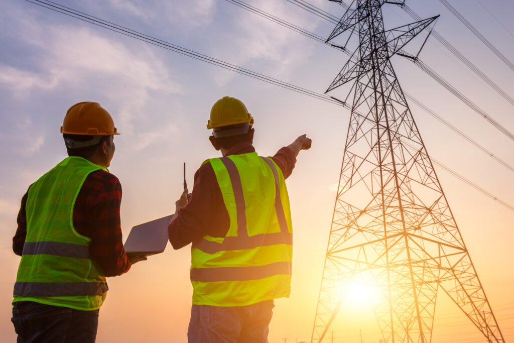 Asian Manager Engineering and worker in standard safety uniform working inspect the electricity high voltage pole.